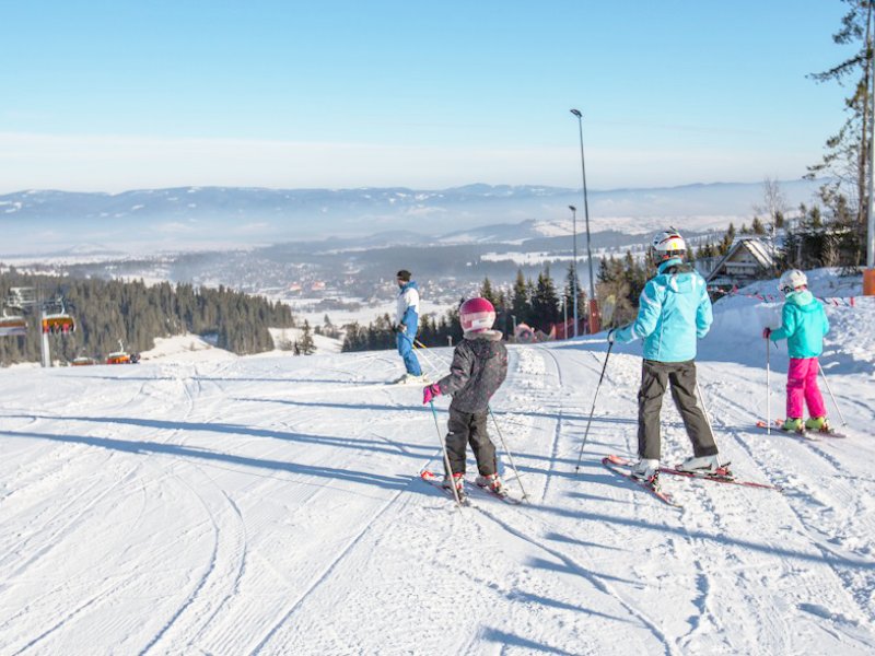 Dzieci z rodzicami uczą zjeżdżają na stoku
